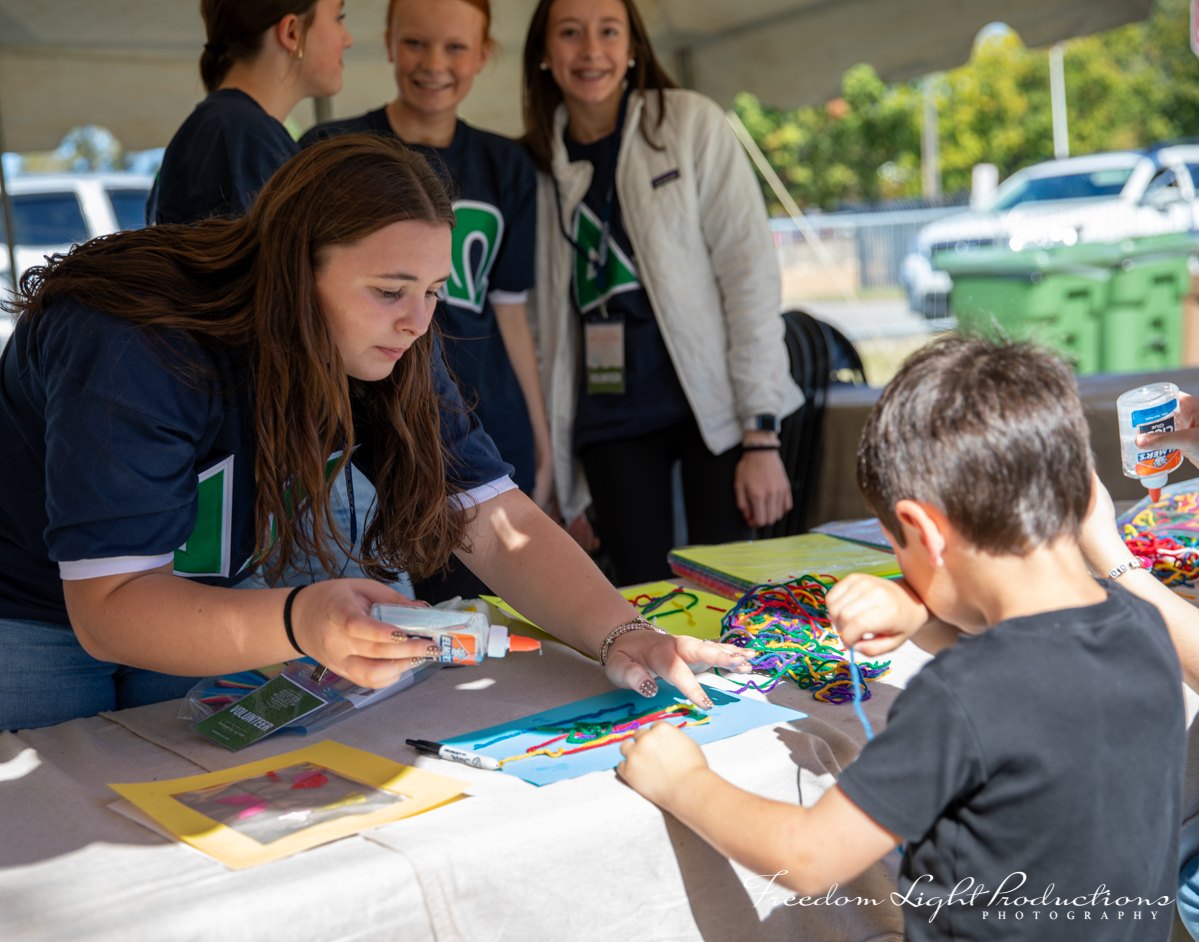 Children and volunteers create colorful artwork in the River Clay children’s art tent