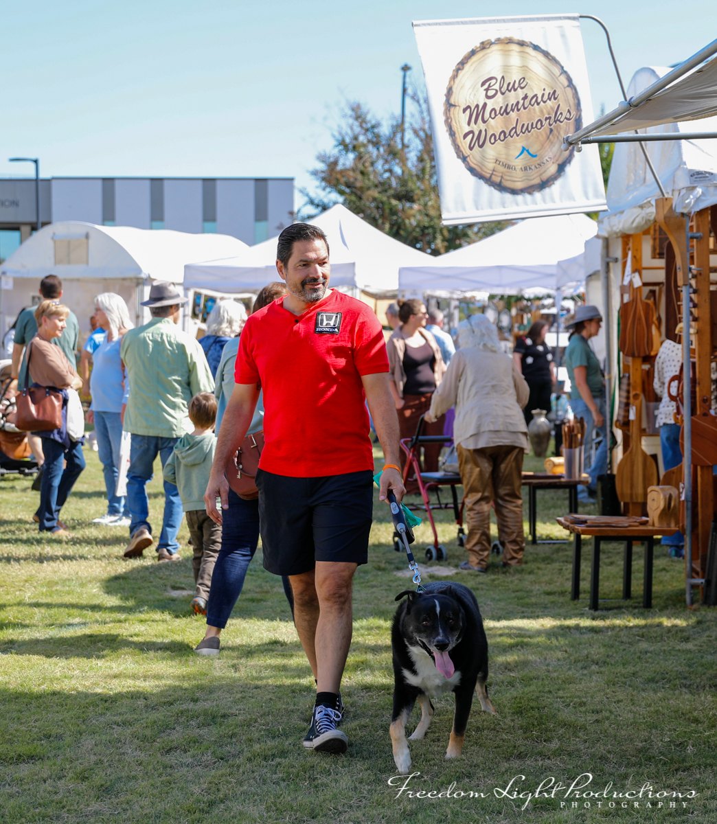 A visitor walks a dog through the River Clay artist market